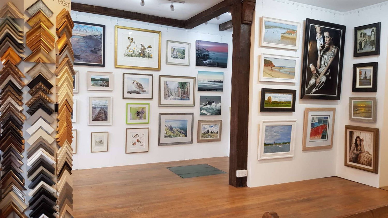 Gallery interior at South Gate Gallery, framed paintings on the back wall with the customer counter